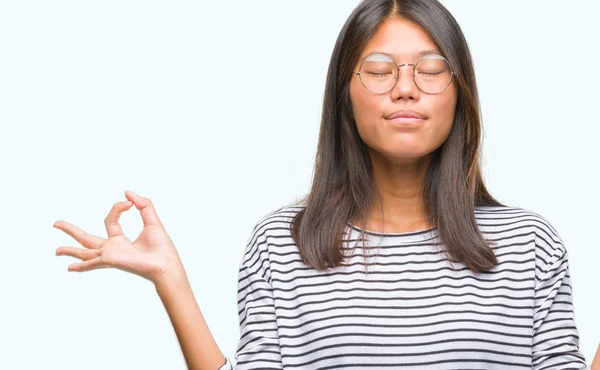 Stock image Young asian woman wearing glasses over isolated background relax and smiling with eyes closed doing meditation gesture with fingers. Yoga concept.