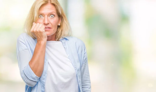 中年金发女人在孤立的背景下 看着压力和紧张的嘴咬指甲的手 焦虑问题 — 图库照片
