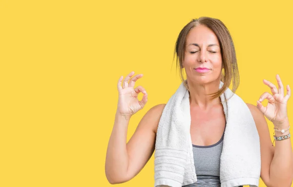 美丽的中年妇女穿着运动服和毛巾在孤立的背景放松和微笑闭着眼睛做冥想手势用手指 瑜伽概念 — 图库照片