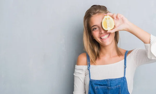 Hermosa Mujer Joven Sobre Pared Gris Grunge Sosteniendo Limón Con —  Fotos de Stock