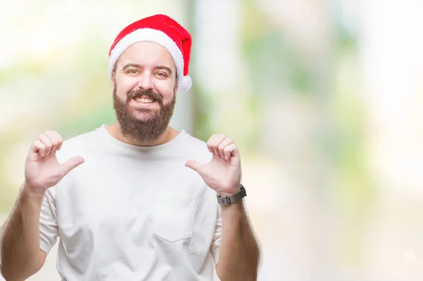 年轻的高加索嬉皮士男子在孤立的背景上戴着圣诞帽 面带微笑 面带微笑 用手指自豪而快乐地指点自己 — 图库照片