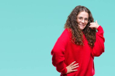 Gözlük ve kış kazak yapıyorsun gülümseyen izole arka plan üzerinde giyen güzel esmer kıvırcık saçlı Genç kız telefon hareketi ile el ve parmak telefonda konuşuyor gibi. Kavramları iletişim.