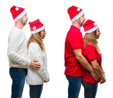 Kolaj orta yaş olgun güzel çift Noel şapka üzerinde beyaz bir arka plan tarafına bakarak izole, doğal yüz emin gülümseme ile pozuyla profil sakin ol.