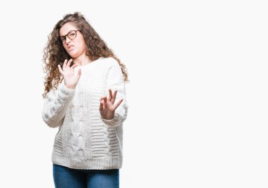 İzole arka plan üzerinde kış kazak giyen güzel esmer kıvırcık saçlı Genç kız tiksinti ifadesi, memnun ve korkulu tiksinti yüz yapıyorsun çünkü nefret tepki. Elleriyle kaldırdı. Sinir bozucu kavramı.