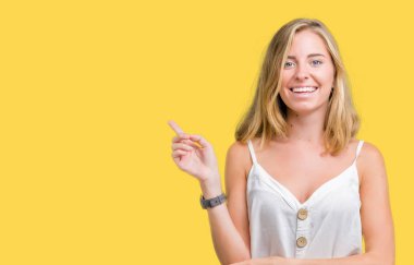 Kameraya bakarak yan el ve parmak ile işaret yüzünde kocaman bir gülümseme ile izole arka plan güzel genç kadın.