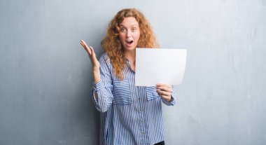 Gri grunge genç Kızıl saçlı kadın duvar büyük gülümseme ile çığlık zaferini kutluyor ve ellerini kaldırdı boş kağıt sayfası çok mutlu ve heyecanlı, kazanan ifade holding