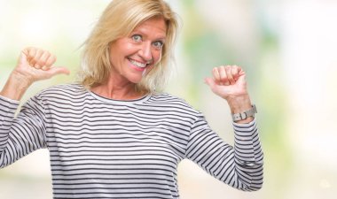 Yüzünde gülümseme ile kendinden emin görünüyorsun, kendini gururlu ve mutlu parmakları ile işaret izole arka plan orta yaş sarışın kadın.