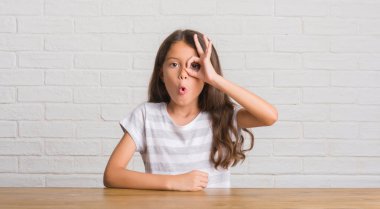 Evde masaya oturan genç İspanyol çocuğun ok jest sürpriz yüz, göz parmaklarının arasından seyir şok işi. İmansız ifade.