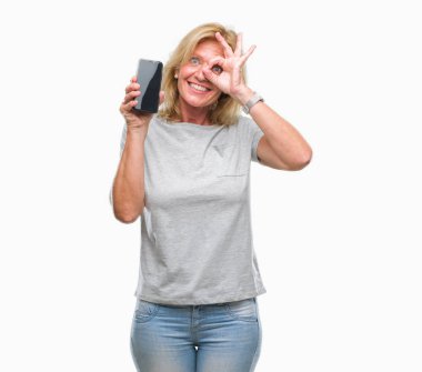 Orta yaş sarışın kadın gösteren boş ekran smartphone ile mutlu yüz el parmaklarının arasından seyir göz üzerinde ok işaretiyle yapıyor gülümseyen izole arka plan üzerinde