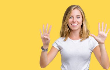 Gösterilen ve parmakları ile işaret izole arka plan üzerinde rahat beyaz t-shirt giyen güzel genç kadın numara 9 kendinden emin ve mutlu gülümseyerek süre.