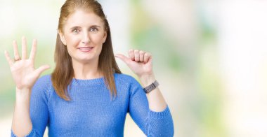 Gösterilen arka plan üzerinde kış kazak giyen güzel orta yaş Olgun kadın izole ve parmakları ile işaret kendinden emin ve mutlu gülümseyerek süre 6 numara.