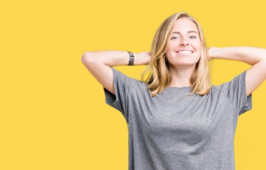 Güzel genç kadın üzerinde büyük boy rahat t-shirt giyen izole arka plan rahatlatıcı ve kollar ve eller baş ve boyun, mutlu gülümseyerek arkasında ile germe