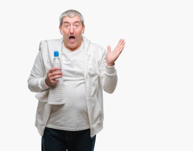 Yakışıklı komuta sizde eğitim holding havlu ve su şişesi üzerinde kocaman bir gülümseme ile çığlık zaferini kutluyor ve ellerini kaldırdı izole arka plan çok mutlu ve heyecanlı, kazanan ifade