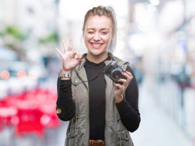 Genç Sarışın kadın parmak, mükemmel sembolü ile ok işareti yapıyor izole arka plan üzerinde Vintage kamera ile fotoğraf çekmek