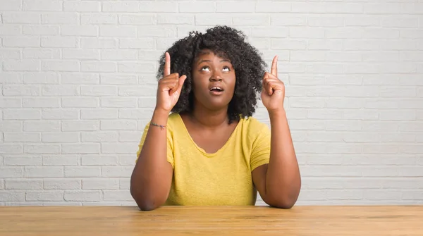 Młody African American Kobieta Siedzi Stole Domu Zdumiony Zaskoczony Patrząc — Zdjęcie stockowe