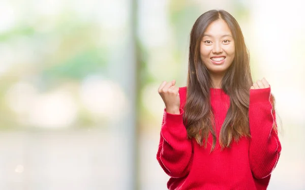 孤立した背景を祝う上冬のセーターを着ている若いアジア女性驚いて腕を上げると成功のため驚くし 目を開きます 勝者の概念 — ストック写真
