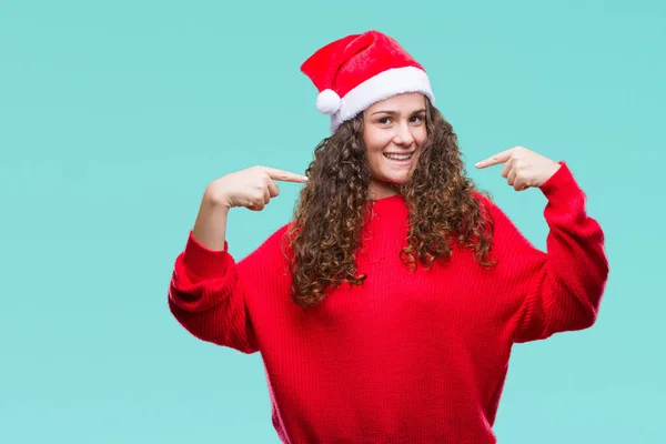年轻的黑发女孩戴着圣诞帽在孤立的背景看起来自信与微笑在脸上 用手指指向自己骄傲和快乐 — 图库照片