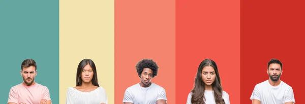 不同民族的年轻人在五颜六色的条纹孤立的背景怀疑和紧张 不赞成的表情在脸上交叉的手臂 消极的人 — 图库照片