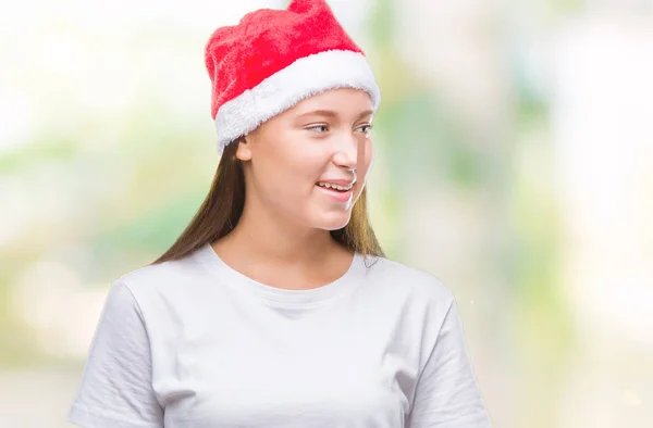 年轻美丽的高加索妇女戴着圣诞帽在孤立的背景看着一边面带微笑 自然的表情 笑自信 — 图库照片