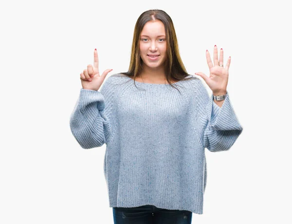 年轻美丽的白人妇女穿着冬季毛衣在孤立的背景显示和指向与手指数字七同时微笑自信和快乐 — 图库照片