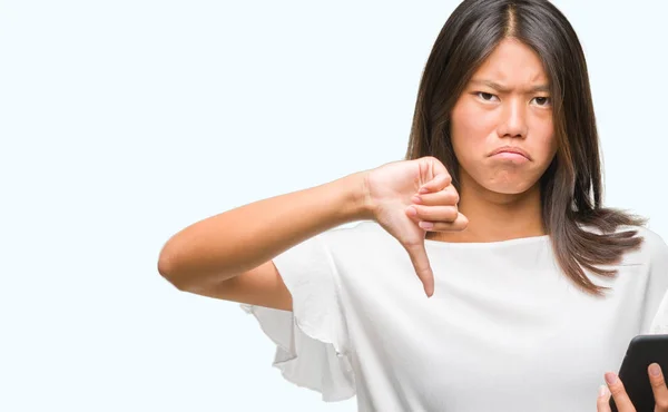 怒った顔 ダウン親指で嫌悪感を示すマイナス記号 拒絶反応の概念と分離の背景にスマート フォンを使用して若いアジア女性のテキスト メッセージ — ストック写真