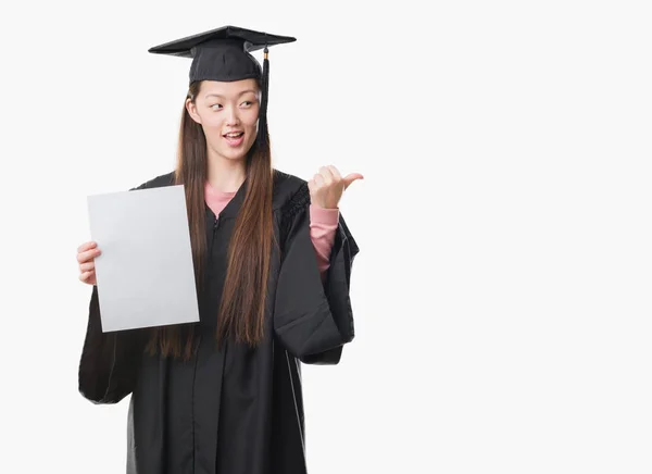 Young Chinese Woman Wearing Graduate Uniform Holding Paper Degree Pointing — Stock Photo, Image