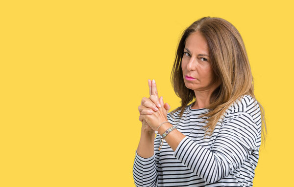 Beautiful middle age woman wearing stripes sweater over isolated background Holding symbolic gun with hand gesture, playing killing shooting weapons, angry face