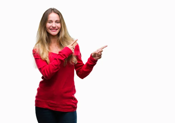 笑顔で側に つの手と指で指しているカメラを見て孤立の背景に赤いセーターを着ている若い美しいブロンドの女性 — ストック写真