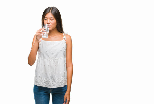 Young asian woman drinking glass of water over isolated background with a confident expression on smart face thinking serious