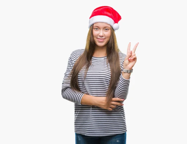 年轻美丽的白人妇女戴着圣诞节帽子在孤立的背景微笑与快乐的脸眨眼在相机做胜利标志 第二个 — 图库照片