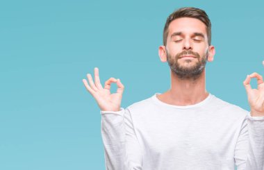 Yakışıklı delikanlı izole arka plan üzerinde dinlenmek ve gülümseyen gözlerle parmak ile meditasyon jest yapıyor kapalı. Yoga kavramı.