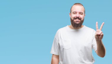 Gösterilen ve parmakları ile işaret izole arka plan üzerinde rahat t-shirt giyen genç beyaz hipster adam ikincisi ise kendinden emin ve mutlu gülümseyerek.