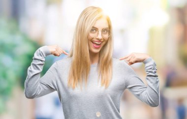 Yüzünde gülümseme ile kendinden emin görünüyorsun, kendini gururlu ve mutlu parmakları ile işaret izole arka plan üzerinde gözlük takan genç güzel sarışın kadın.