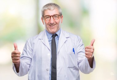 Yakışıklı kıdemli Doktor, el ile pozitif jest yapıyor izole arka plan başarı işareti üzerinde beyaz önlük giyen bilim adamı profesyonel adam gülümsüyor ve mutlu yaşasın. Neşeli bir ifadeyle, kazanan jest kameraya bakıyor.