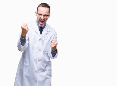 Gülümseyen ve başarı için çığlık çok mutlu ve heyecanlı kaldırdı, silah ile kazanan jest yapıyor izole arka plan üzerinde beyaz önlük giyen orta yaş üst düzey ağarmış profesyonel bir adam. Kutlama kavramı.