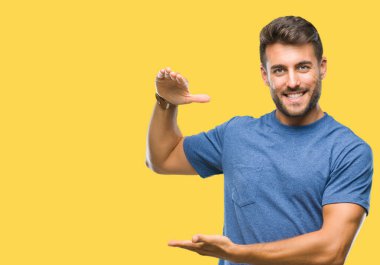 Yakışıklı delikanlı ile büyük ve büyük boy işaret, ölçü birimi sembol gösteren el eller izole arka plan üzerinde. Kameraya bakarak gülümsüyordu. Ölçüm kavramı.