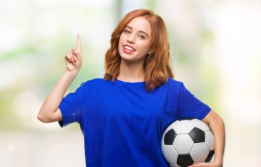 İzole arka plan futbol futbol topu sürpriz bir fikir ya da soru işaret parmağı ile gülen yüz, bir numara tutan genç güzel kadın
