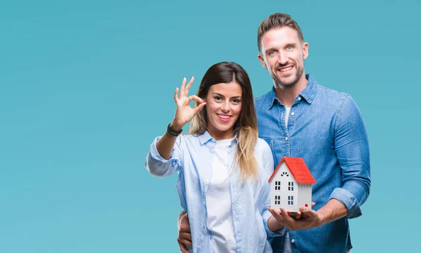 Jovem Casal Apaixonado Segurando Casa Sobre Fundo Isolado Fazendo Sinal — Fotografia de Stock