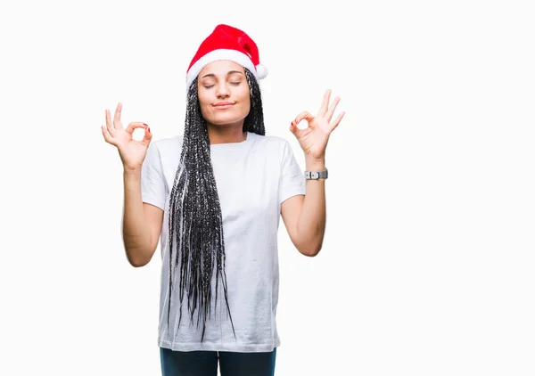 年轻的编织头发非洲裔美国女孩戴着孤立的背景的圣诞帽放松和微笑 闭着眼睛用手指做冥想手势 瑜伽概念 — 图库照片