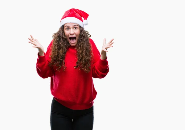 若いブルネットの女の子のクリスマスの帽子をかぶって狂気を祝う背景を分離した腕を上げると成功のためびっくりし 叫んで興奮して目を開きます 勝者の概念 — ストック写真