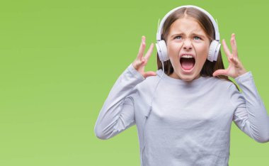 Üzerinden müzik kulaklık giyen genç güzel kız arka plan deli izole ve deli bağırarak ve agresif ifade ve silah kaldırdı bağırıyor. Hayal kırıklığı kavramı.