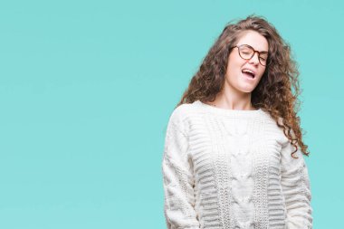 Seksi bir ifadeyle, neşeli ve mutlu yüzünü kameraya bakarak göz kırpıyor izole arka plan üzerinde kış kazak giyen güzel esmer kıvırcık saçlı Genç kız.