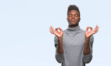 Genç Afro-Amerikan adam izole arka plan üzerinde dinlenmek ve gülümseyen gözlerle parmak ile meditasyon jest yapıyor kapalı. Yoga kavramı.