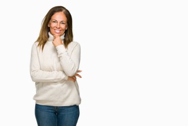Emin çapraz kollar ve çeneme kaldırdı el ile gülümseme ile kameraya bakarak izole arka plan üzerinde kış kazak giyen güzel orta yaş yetişkin kadın. Pozitif düşünce.