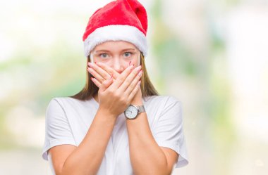 Üzerinde Noel şapka giyen genç güzel beyaz kadın arka plan ağız hata için elleriyle kapsayan şok izole. Gizli kavramı.