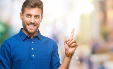 Kameraya bakarak yan el ve parmak ile işaret eden genç yakışıklı adam yüzünde kocaman bir gülümseme ile izole arka plan üzerinde.