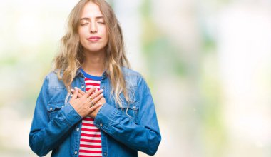 Güzel genç sarışın kadın ile gülümseyen izole arka plan üzerinde kapalı gözler ve yüzünde minnettar jest ile göğüs üzerinde eller. Sağlık kavramı.