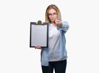 Genç beyaz iş kadın holding Pano kamera ve size parmak ile işaret izole arka plan üzerinde el işareti, pozitif ve kendinden emin bir jest ön