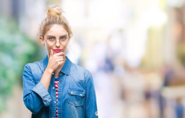Emin çapraz kollar ve çeneme kaldırdı el ile gülümseme ile kameraya bakarak izole arka plan üzerinde gözlük takan genç güzel sarışın kadın. Pozitif düşünce.