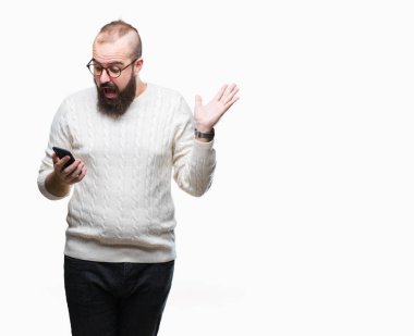 Genç beyaz hipster adam manifatura üzerinden Smartphone kullanarak ileti gönderme büyük gülümseme ile çığlık zaferini kutluyor arka plan çok mutlu ve heyecanlı, kazanan ifade izole ve ellerini kaldırdı